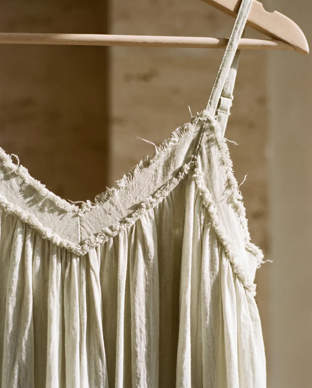 Cream linen dress detail on a wooden hanger