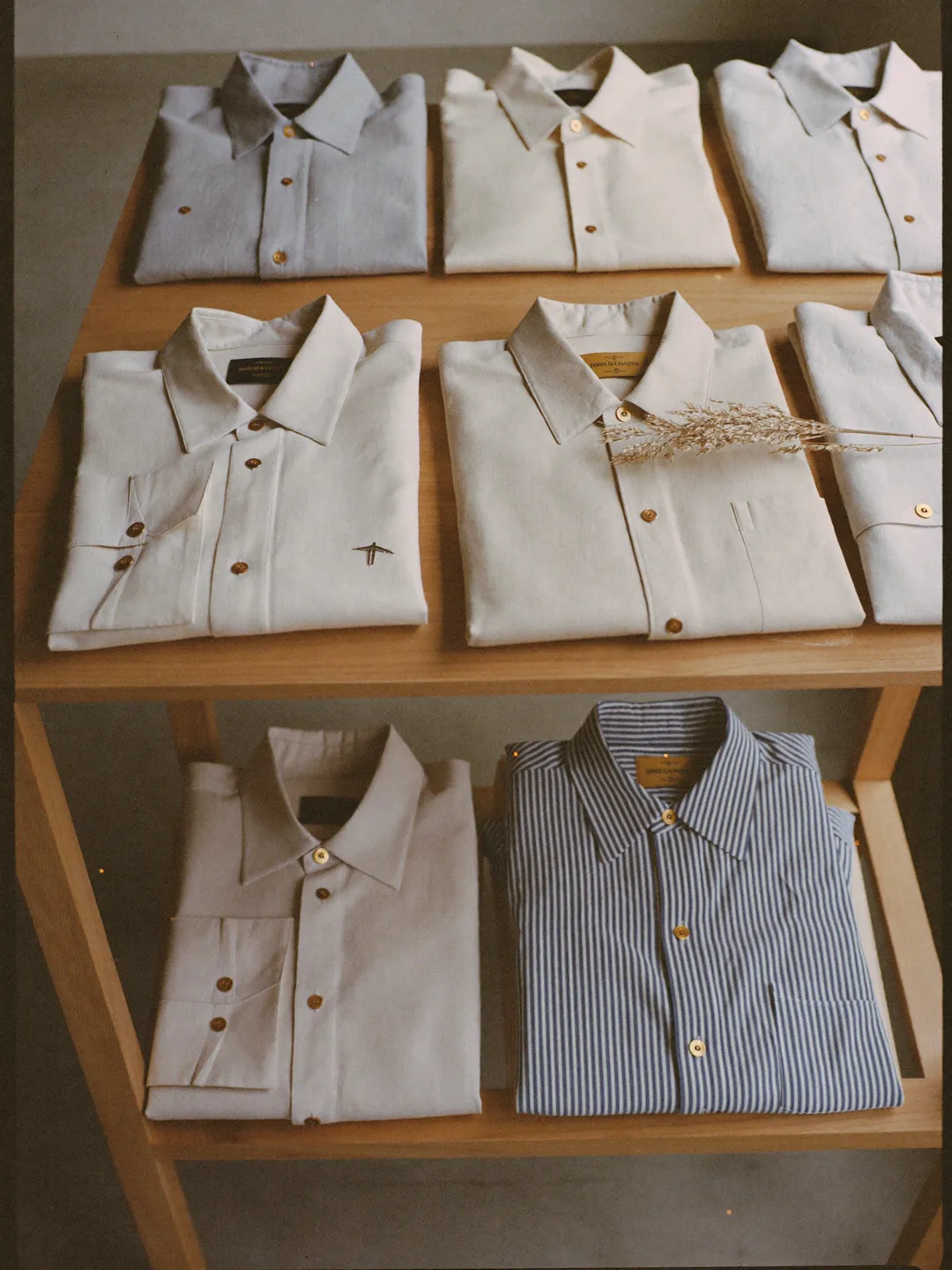 Folded linen shirts in cream and dusty blue on a boutique shelf